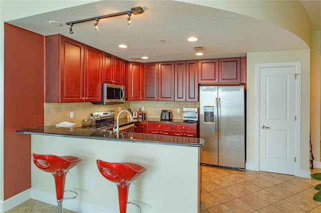 101 S Eola Dr Unit 1021, Orlando, FL 32801 - kitchen featuring stainless steel appliances, dark brown cabinets, arched walkways, dark countertops, and tasteful backsplash