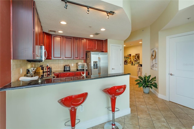 101 S Eola Dr Unit 1021, Orlando, FL 32801 - kitchen featuring stainless steel fridge with ice dispenser, a peninsula, dark brown cabinets, light tile patterned floors, and backsplash