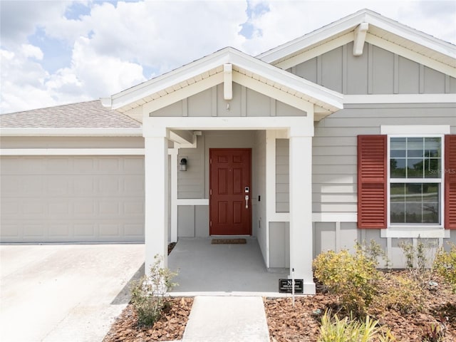 561 Andrea Cir S, Haines City, FL 33844 - property entrance with board and batten siding, a garage, a shingled roof, and driveway
