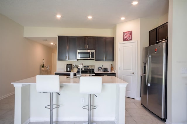 561 Andrea Cir S, Haines City, FL 33844 - kitchen with stainless steel appliances, an island with sink, a breakfast bar, dark brown cabinetry, and recessed lighting