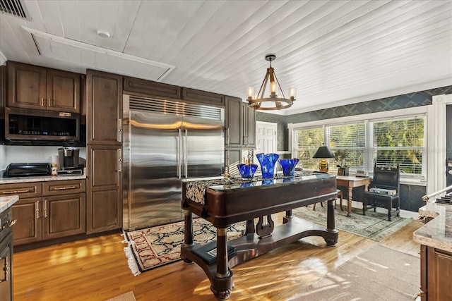 8407 Interbay Blvd, Tampa, FL 33616 - kitchen with appliances with stainless steel finishes, light wood finished floors, a chandelier, and light stone counters