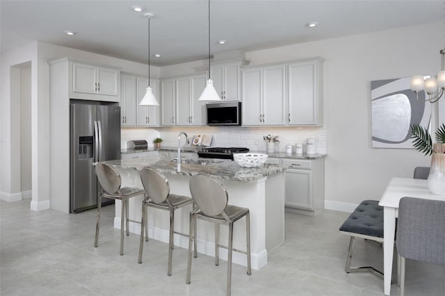 2380 Celebration Blvd, Celebration, FL 34747 - kitchen featuring appliances with stainless steel finishes, light stone counters, tasteful backsplash, a breakfast bar, and an island with sink