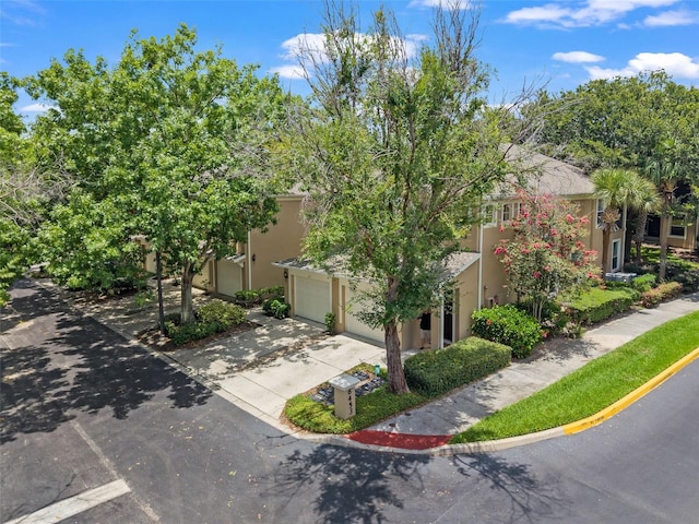 6453 Alcalde Ct Unit 110, Orlando, FL 32835 - view of property hidden behind natural elements featuring a garage, driveway, and stucco siding