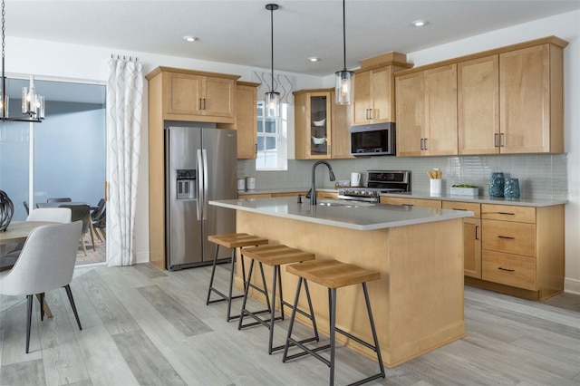 2386 Celebration Blvd, Celebration, FL 34747 - kitchen featuring appliances with stainless steel finishes, light wood-style floors, light countertops, a kitchen bar, and recessed lighting