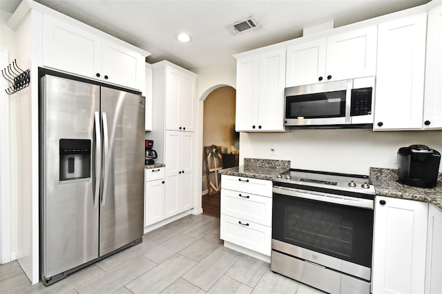 26 Canter Club Ct, Debary, FL 32713 - kitchen featuring stainless steel appliances, arched walkways, white cabinets, dark stone counters, and recessed lighting