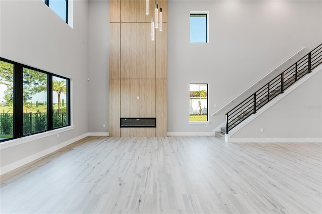 15942 Vetta Dr, Bella Collina, FL 34756 - unfurnished living room featuring a towering ceiling, stairs, light wood-style flooring, and a fireplace