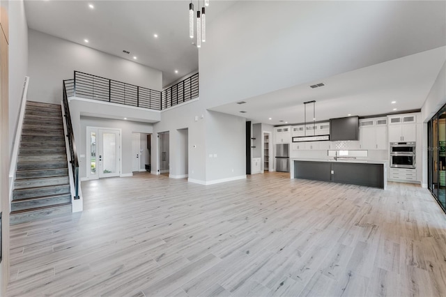 15942 Vetta Dr, Bella Collina, FL 34756 - unfurnished living room featuring a high ceiling, light wood-type flooring, stairway, and recessed lighting