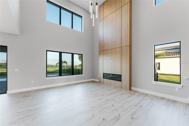 15942 Vetta Dr, Bella Collina, FL 34756 - unfurnished living room featuring a towering ceiling, healthy amount of natural light, a large fireplace, and light wood-style flooring