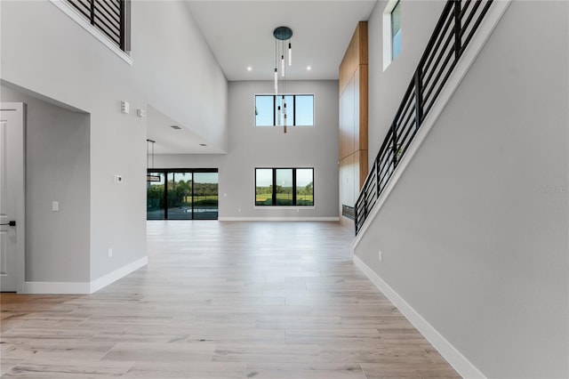 15942 Vetta Dr, Bella Collina, FL 34756 - unfurnished living room featuring light wood finished floors, stairway, a towering ceiling, and recessed lighting