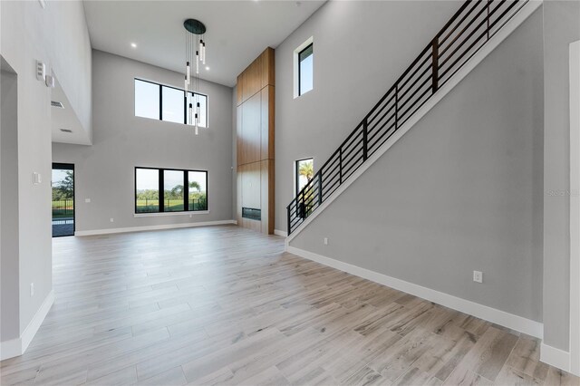 15942 Vetta Dr, Bella Collina, FL 34756 - unfurnished living room featuring a high ceiling, light wood-style floors, stairway, and recessed lighting