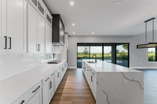 15942 Vetta Dr, Bella Collina, FL 34756 - kitchen featuring stainless steel gas cooktop, light wood finished floors, a kitchen island with sink, backsplash, and recessed lighting