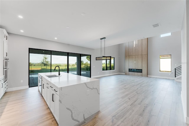 15942 Vetta Dr, Bella Collina, FL 34756 - kitchen with open floor plan, light wood-style flooring, stainless steel double oven, recessed lighting, and a center island with sink