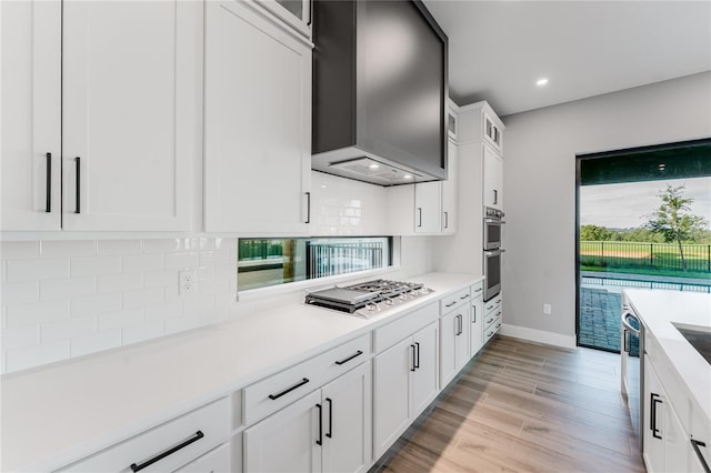15942 Vetta Dr, Bella Collina, FL 34756 - kitchen featuring stainless steel appliances, wall chimney range hood, tasteful backsplash, light countertops, and recessed lighting