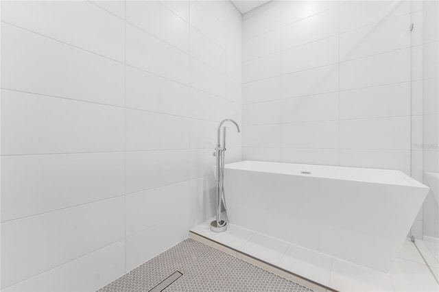 15942 Vetta Dr, Bella Collina, FL 34756 - bathroom with a freestanding tub, tile walls, and tile patterned flooring