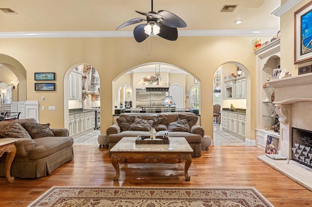 9400 Laws Rd, Clermont, FL 34714 - living area featuring arched walkways, ceiling fan, crown molding, light wood-style flooring, and built in shelves