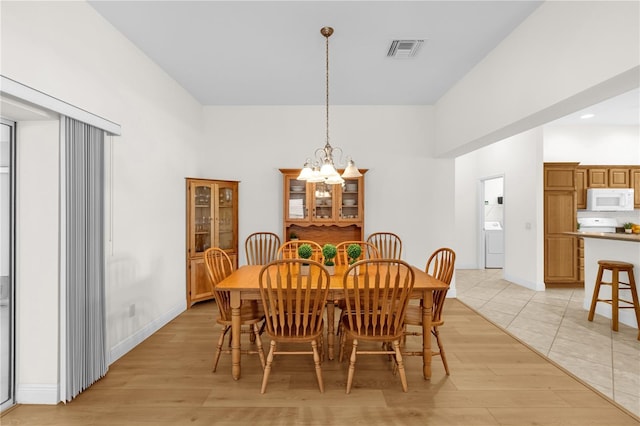 1254 Spartanburg Way, The Villages, FL 32162 - dining room featuring washer / dryer, a chandelier, light wood finished floors, and a towering ceiling