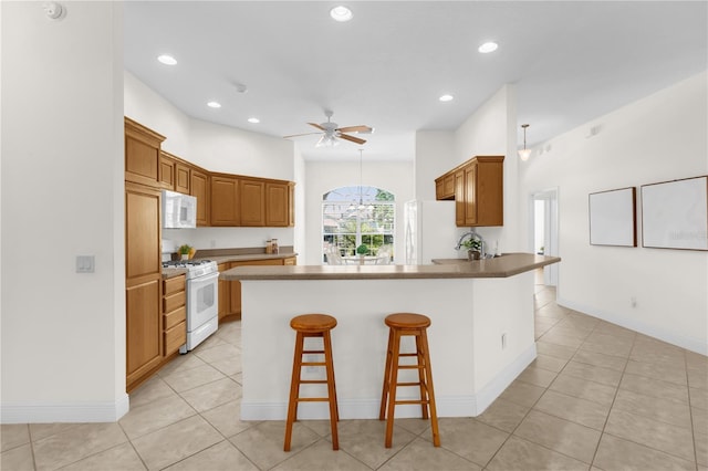 1254 Spartanburg Way, The Villages, FL 32162 - kitchen featuring white appliances, a peninsula, a ceiling fan, a kitchen bar, and recessed lighting