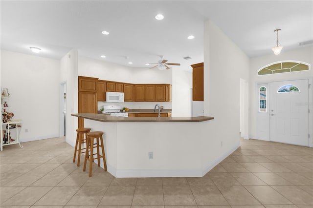 1254 Spartanburg Way, The Villages, FL 32162 - kitchen with white appliances, brown cabinetry, light tile patterned floors, a ceiling fan, and recessed lighting