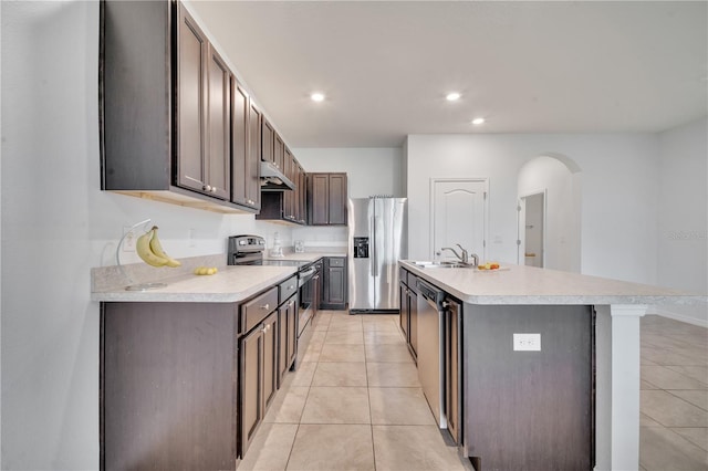 200 Feltrim Reserve Blvd, Davenport, FL 33837 - kitchen featuring appliances with stainless steel finishes, light countertops, light tile patterned floors, arched walkways, and a center island with sink