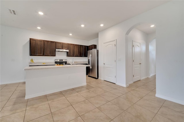 200 Feltrim Reserve Blvd, Davenport, FL 33837 - kitchen with appliances with stainless steel finishes, under cabinet range hood, dark brown cabinetry, light countertops, and arched walkways
