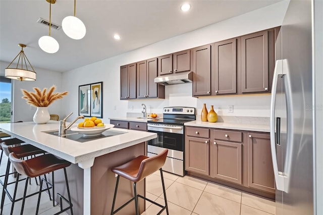 200 Feltrim Reserve Blvd, Davenport, FL 33837 - kitchen with stainless steel appliances, under cabinet range hood, light countertops, a breakfast bar, and hanging light fixtures