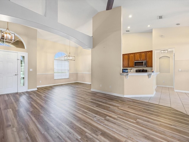 14322 Pine Cone Trl, Clermont, FL 34711 - unfurnished living room featuring a chandelier, high vaulted ceiling, and light wood-type flooring