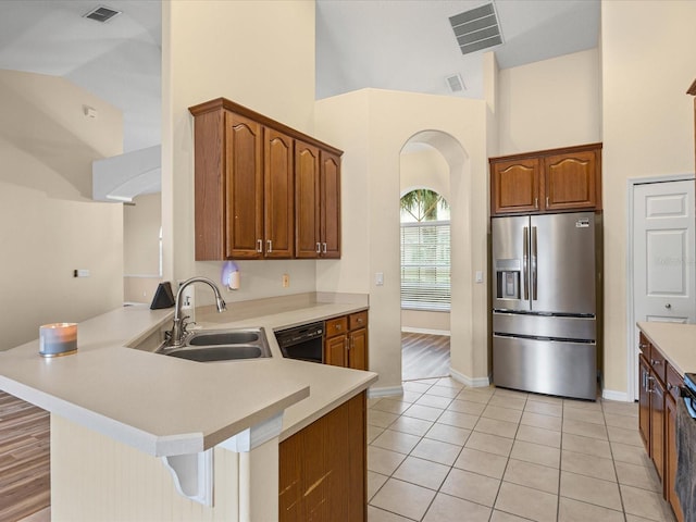 14322 Pine Cone Trl, Clermont, FL 34711 - kitchen with stainless steel refrigerator with ice dispenser, arched walkways, black dishwasher, a peninsula, and high vaulted ceiling