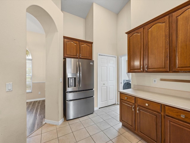 14322 Pine Cone Trl, Clermont, FL 34711 - kitchen featuring stainless steel fridge, washer / dryer, light countertops, light tile patterned floors, and brown cabinetry