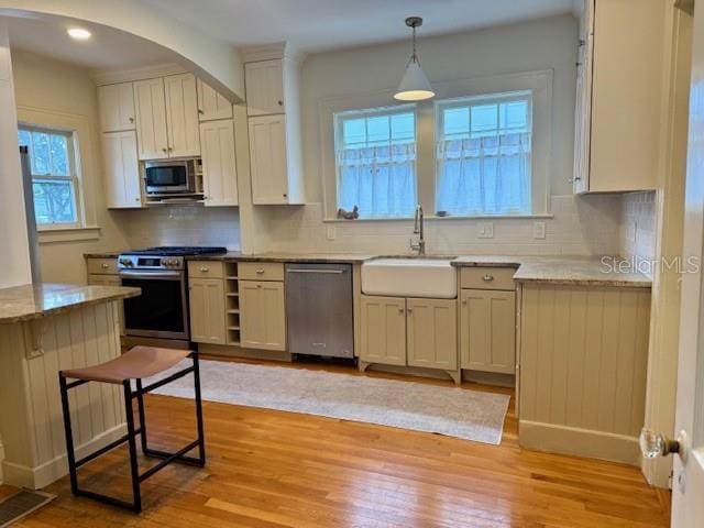 501 Richmond St, Orlando, FL 32806 - kitchen with stainless steel appliances, arched walkways, light wood finished floors, decorative backsplash, and recessed lighting