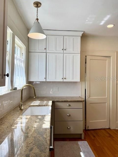 501 Richmond St, Orlando, FL 32806 - kitchen with backsplash, pendant lighting, white cabinetry, wood finished floors, and light stone counters