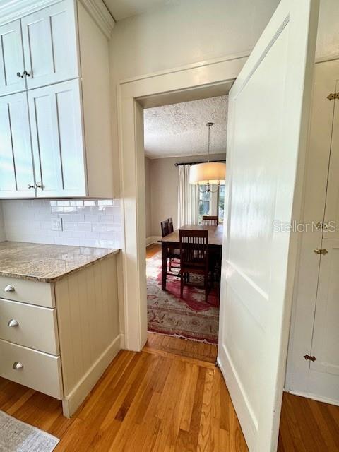 501 Richmond St, Orlando, FL 32806 - kitchen with light wood-style floors, decorative backsplash, white cabinets, light stone countertops, and a textured ceiling