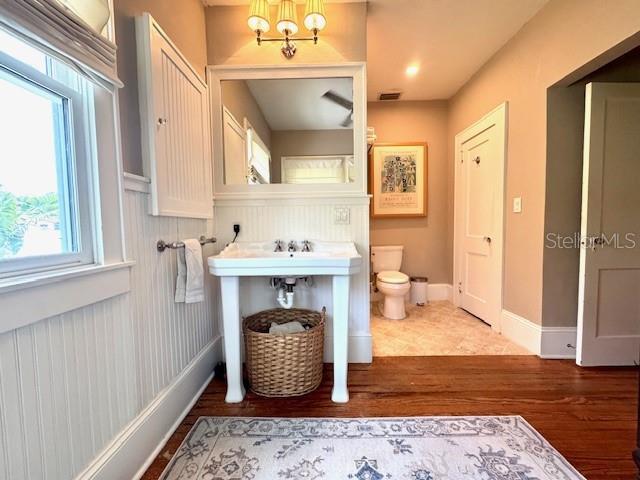 501 Richmond St, Orlando, FL 32806 - bathroom featuring wood finished floors, a chandelier, and a wainscoted wall