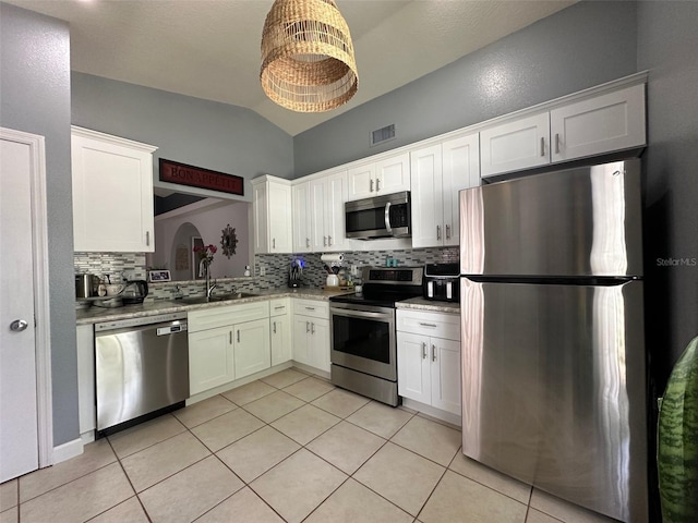 1470 Daniels Cove Dr, Winter Garden, FL 34787 - kitchen with stainless steel appliances, decorative backsplash, lofted ceiling, light tile patterned flooring, and white cabinetry