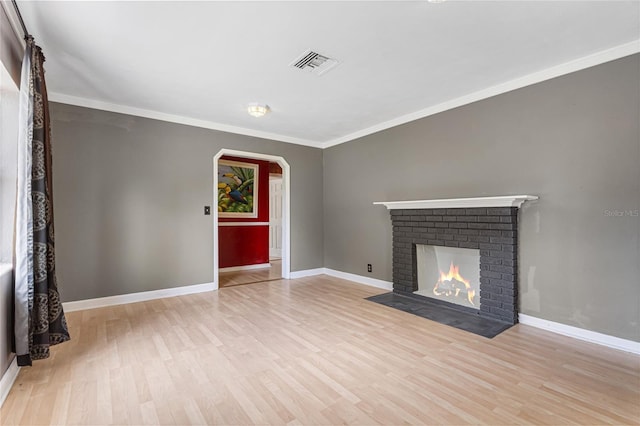 1104 W Marjorie St, Lakeland, FL 33815 - unfurnished living room featuring arched walkways, wood finished floors, crown molding, and a fireplace