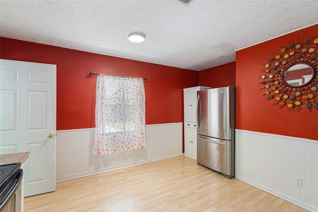 1104 W Marjorie St, Lakeland, FL 33815 - kitchen featuring freestanding refrigerator, electric range, a wainscoted wall, light wood finished floors, and a textured ceiling
