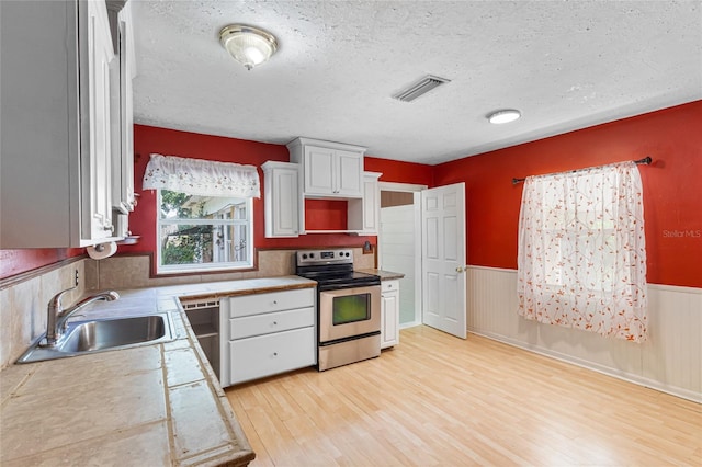1104 W Marjorie St, Lakeland, FL 33815 - kitchen with appliances with stainless steel finishes, light wood-type flooring, a wainscoted wall, a textured ceiling, and light countertops