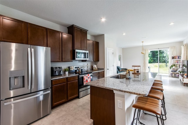 5029 Grand Teton Ct, Deland, FL 32724 - kitchen with appliances with stainless steel finishes, a kitchen breakfast bar, light stone countertops, an island with sink, and dark brown cabinets