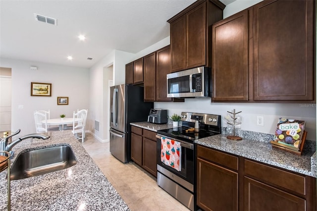 5029 Grand Teton Ct, Deland, FL 32724 - kitchen featuring appliances with stainless steel finishes, dark brown cabinetry, light stone counters, light tile patterned flooring, and recessed lighting
