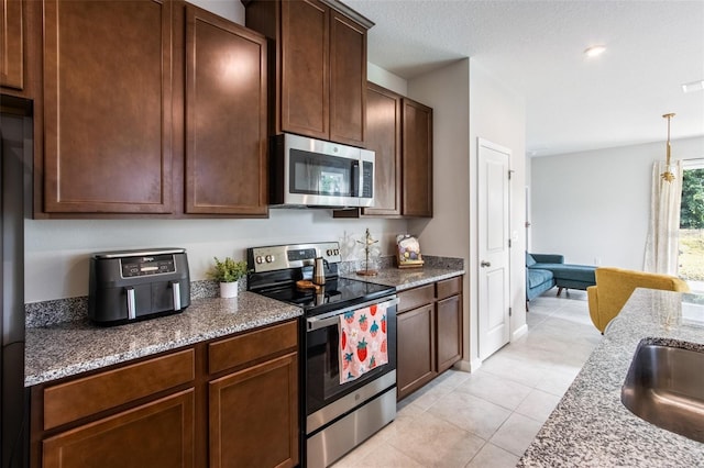 5029 Grand Teton Ct, Deland, FL 32724 - kitchen featuring appliances with stainless steel finishes, light tile patterned floors, light stone countertops, pendant lighting, and dark brown cabinets