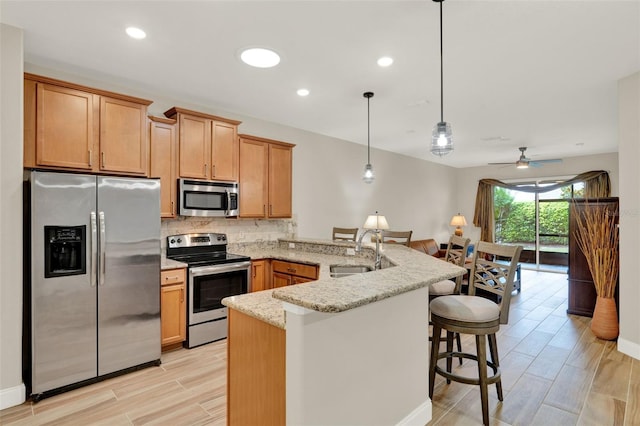 3210 Sonesta Ct Unit B, Clermont, FL 34711 - kitchen with appliances with stainless steel finishes, a peninsula, decorative backsplash, a kitchen bar, and light stone counters
