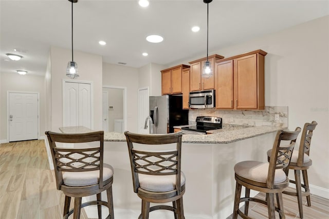 3210 Sonesta Ct Unit B, Clermont, FL 34711 - kitchen featuring stainless steel appliances, backsplash, light wood-style flooring, a breakfast bar area, and brown cabinets