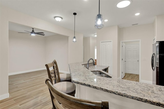 3210 Sonesta Ct Unit B, Clermont, FL 34711 - kitchen with freestanding refrigerator, light wood-style floors, a kitchen breakfast bar, hanging light fixtures, and light stone countertops