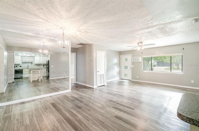 1422 Russell Ave, Orlando, FL 32806 - unfurnished living room with a textured ceiling, ceiling fan, a chandelier, and light wood-type flooring