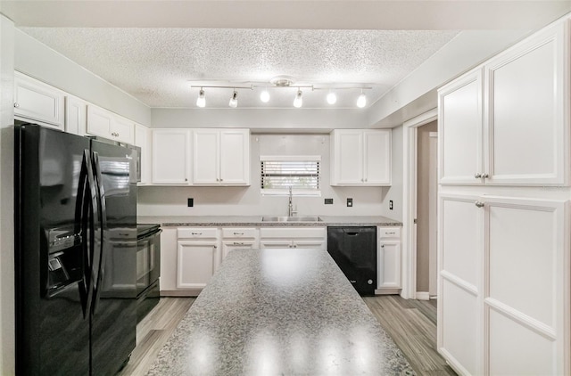 1422 Russell Ave, Orlando, FL 32806 - kitchen with black appliances, white cabinetry, light wood-type flooring, and a textured ceiling
