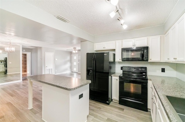 1422 Russell Ave, Orlando, FL 32806 - kitchen with black appliances, a textured ceiling, light wood-style floors, white cabinetry, and track lighting