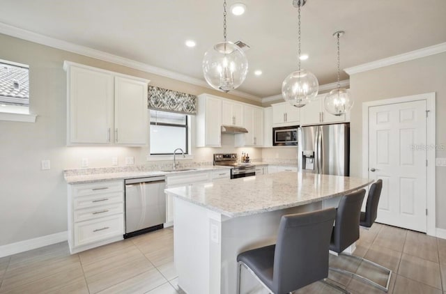 13084 Rinella St, Venice, FL 34293 - kitchen featuring appliances with stainless steel finishes, a kitchen island, white cabinets, crown molding, and a breakfast bar area