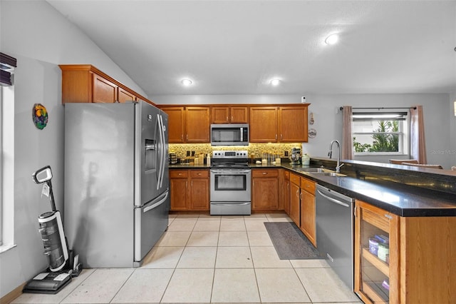 14566 Quail Trail Cir, Orlando, FL 32837 - kitchen with appliances with stainless steel finishes, brown cabinetry, decorative backsplash, a peninsula, and light tile patterned floors