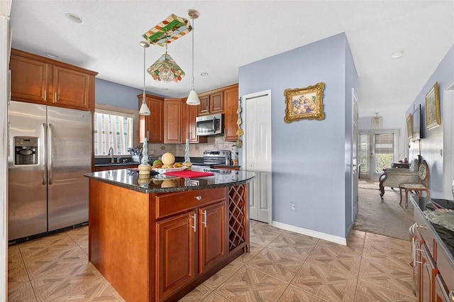 2076 Shannon Lakes Blvd, Kissimmee, FL 34743 - kitchen featuring appliances with stainless steel finishes, a center island, decorative backsplash, pendant lighting, and dark stone counters