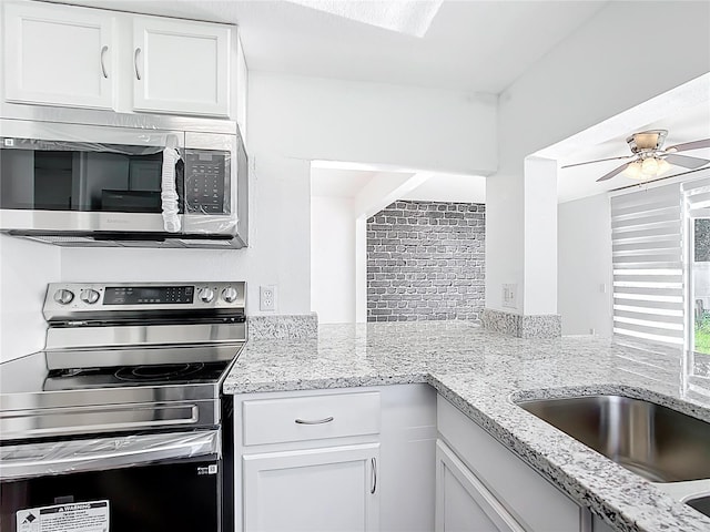709 Orchid Dr, Davenport, FL 33897 - kitchen featuring appliances with stainless steel finishes, white cabinetry, a ceiling fan, and light stone counters