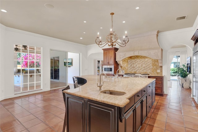 3130 Butler Bay Dr N, Windermere, FL 34786 - kitchen with stainless steel microwave, decorative backsplash, light tile patterned floors, a kitchen island with sink, and crown molding